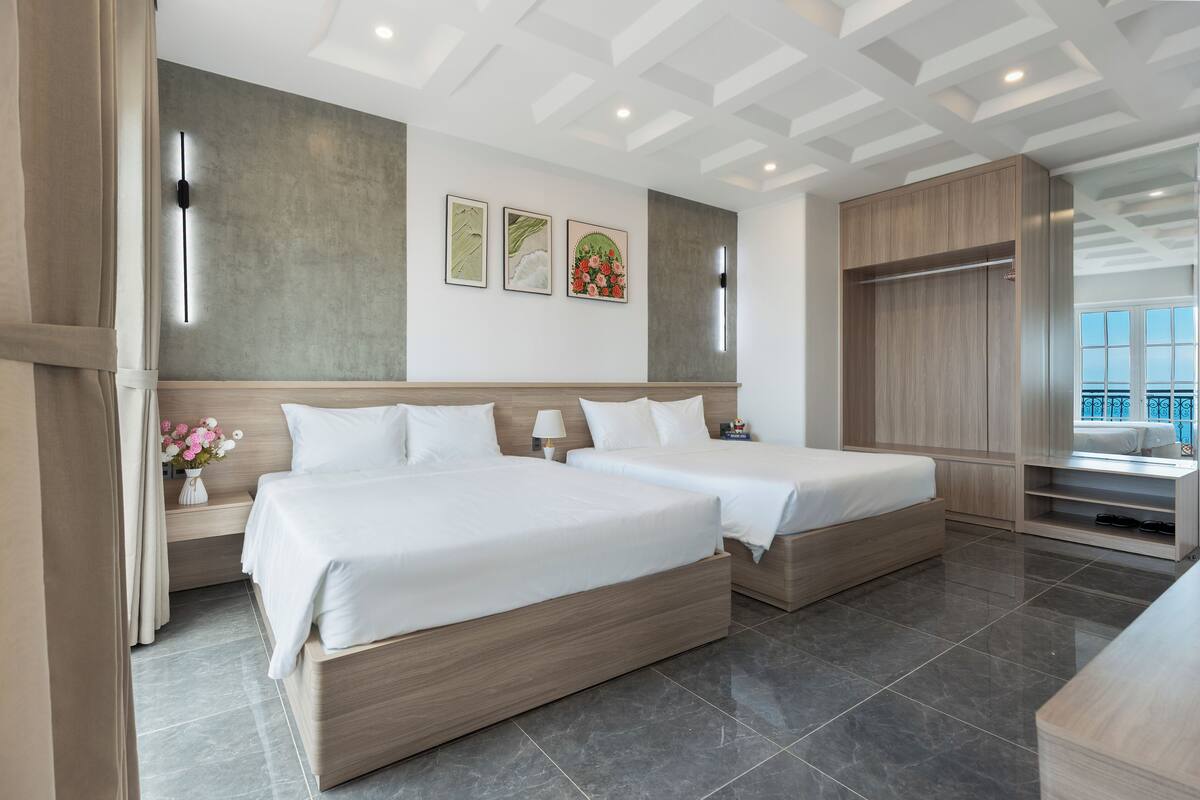 Una habitación de hotel con dos camas, un armario, un tocador y un ventanal grande.