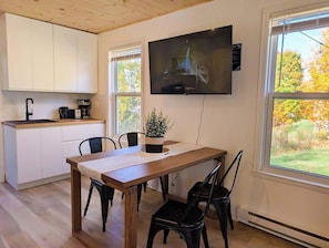 Eine moderne Küche mit weißen Schränken, einem Holztisch und einem Wand-Fernseher.