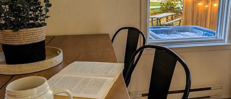 A wooden table with a potted plant, a mug, and an open book.