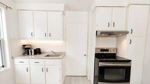 Una cucina moderna con mobili bianchi, una cappa aspirante in acciaio inossidabile e un forno integrato.