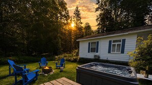 Un giardino sul retro con idromassaggio, terrazza in legno e poltrone Adirondack.