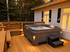 Eine Holzterrasse mit Whirlpool, einer Holzbank und einem kleinen Tisch.