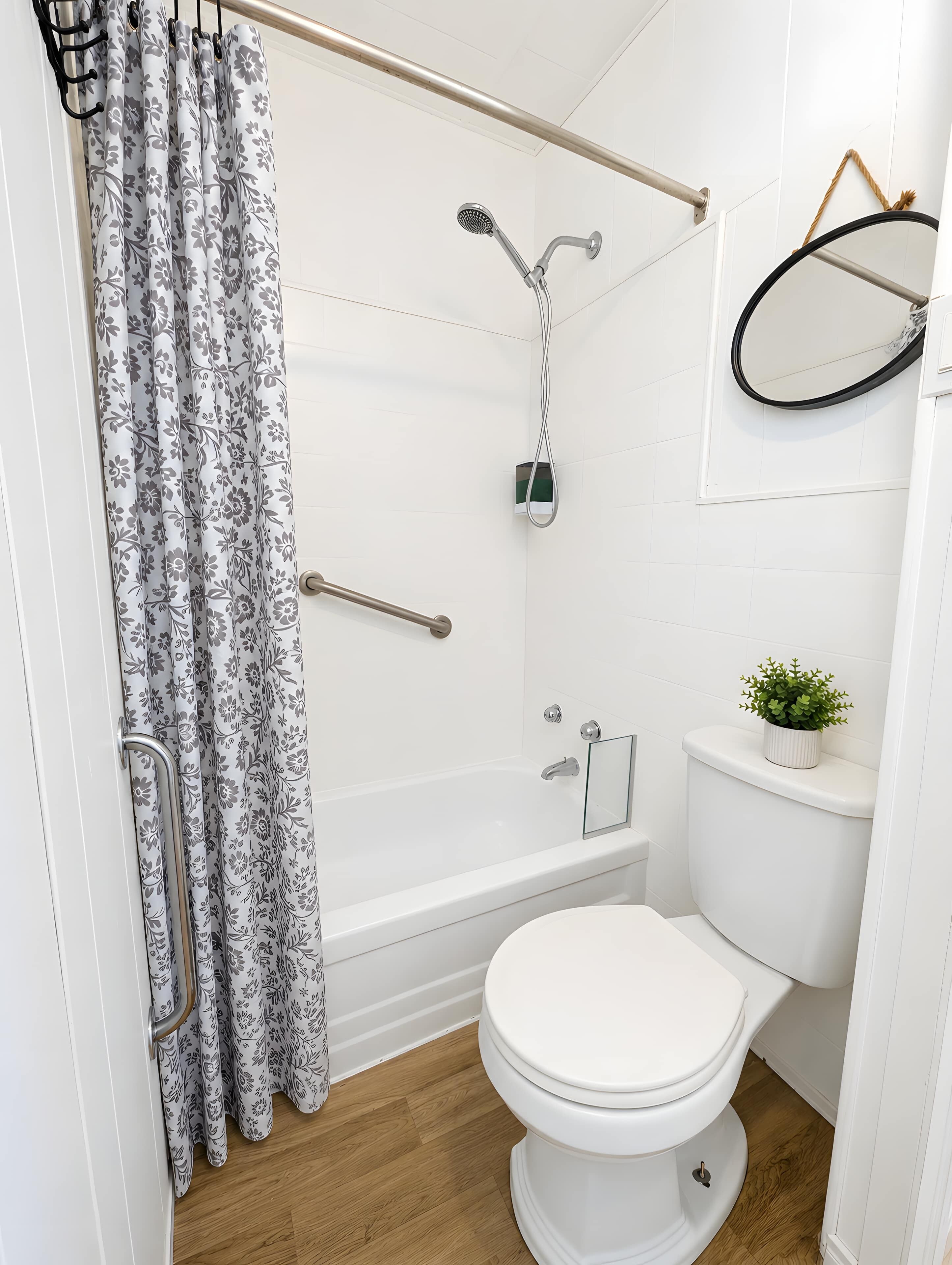 Et badeværelse med bruser, toilet og en lille potteplante.