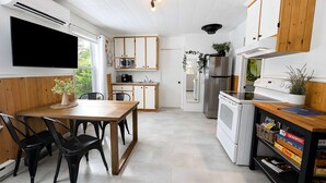 Et moderne køkken med spiseplads, indbyggede apparater og et fladskærms-tv.