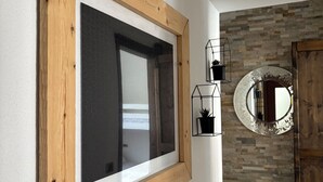 Ein Zimmer mit einem Fenster aus Holz, einer Steinwand und einer Holztür.