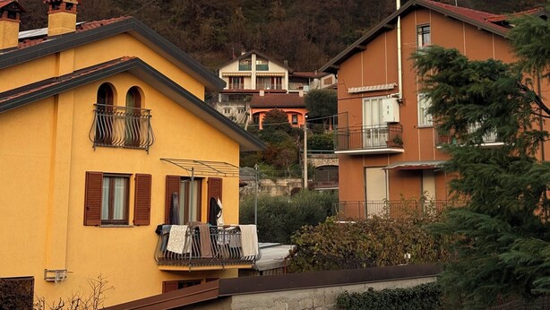 Ein Wohngebiet mit Häusern, einem Balkon und einem Berg im Hintergrund.