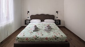 Ein Einzelbett mit blumigem Überwurf, zwei Nachttische, ein Fenster mit Vorhängen und eine Deckenleuchte.