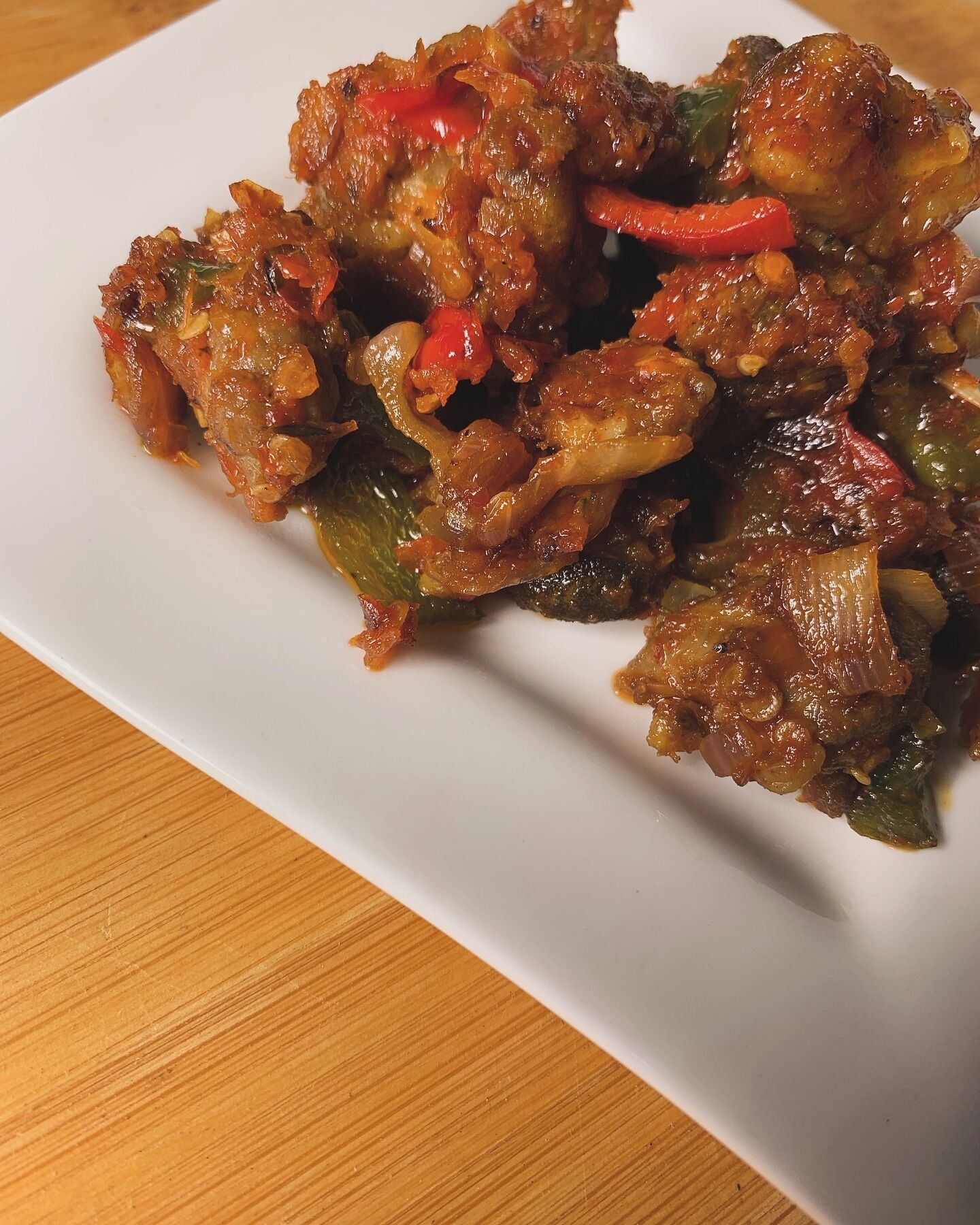 Un plato blanco rectangular con un guiso de verduras y carne.