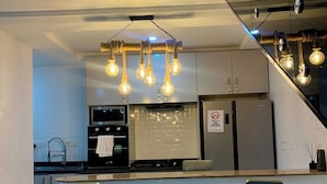 Una cocina moderna con una isla central, electrodomésticos de acero inoxidable y una lámpara original.