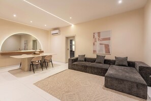 Una sala de estar moderna con comedor, un sofá grande y una alfombra.