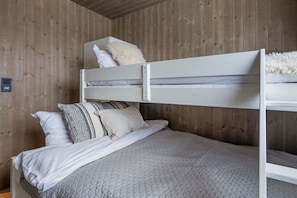 A bunk bed with a white headboard, a lower bed with a quilted blanket, and two pillows with geometric patterns. - GO334A- Trysil Ski-in/out Apt, 4 BR (Trysil)