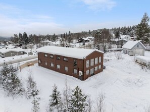 Ein großes, rechteckiges Gebäude mit zahlreichen Fenstern, umgeben von schneebedeckten Bäumen und Häusern.