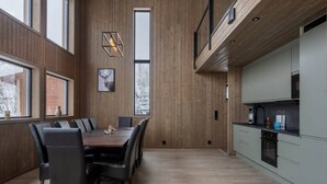 A modern kitchen with a built-in oven and a dining area with a wooden table and chairs. - Trysil Ski-in/out Apt, Hot Tub, 4 BR (Trysil)