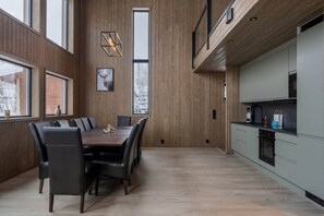 Eine moderne Küche mit eingebautem Ofen und einem Essbereich mit einem Holztisch und Stühlen.