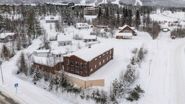 A snow-covered building complex with multiple structures, surrounded by trees and a ski slope in the background. - Trysil Ski-in/out Apt, Hot Tub, 4 BR (Trysil)