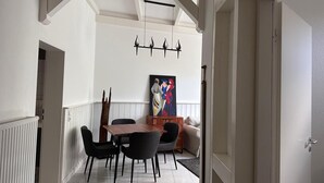 Ein Essbereich mit Holztisch und Stühlen, einem Bild an der Wand und einer Deckenleuchte.