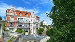 Ein mehrgeschossiges Gebäude mit rotem Ziegeldach, Balkonen und einem Garten.