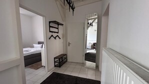 Ein Flur mit einem Bett, einer Bank, einem Kleiderständer und einem Spiegel.