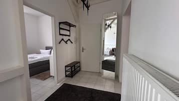 Un corridoio con un letto, una panca, un appendiabiti e uno specchio.