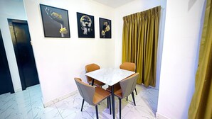 Ein Essbereich mit Marmorfliesen, einem weißen Tisch mit vier Stühlen und drei gerahmten Kunstwerken an der Wand.