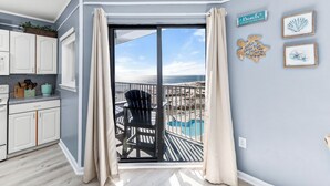 A room with a view of the beach, a sliding glass door, a pool, and a kitchen area. - Gulf Shores Plantation, 5508 - Beachfront Condo with Gulf Views (Gulf Shores)