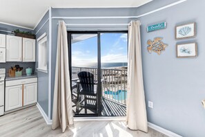 Ein Zimmer mit Blick auf den Strand, einer Schiebetür, einem Pool und einer Küchenzeile.