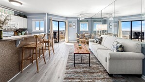 A modern living room with a sofa, coffee table, and dining area. - Gulf Shores Plantation, 5508 - Beachfront Condo with Gulf Views (Gulf Shores)