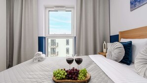 Habitación de hotel con cama, mesita de noche, ventana y vista a edificios.
