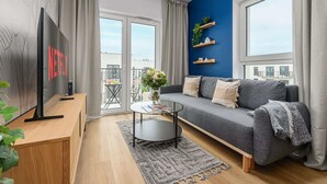Una sala de estar moderna con un sofá gris, una mesa de centro, un televisor de pantalla plana y un balcón con vistas.