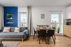 A modern apartment with a dining area, a sofa, and a kitchen.