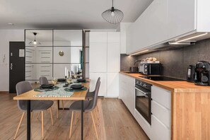 Una cocina moderna con encimera de madera, electrodomésticos integrados y un comedor con mesa preparada para dos personas.