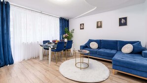 Un salon moderne avec un canapé bleu, une table basse ronde et un coin repas avec des chaises bleues.