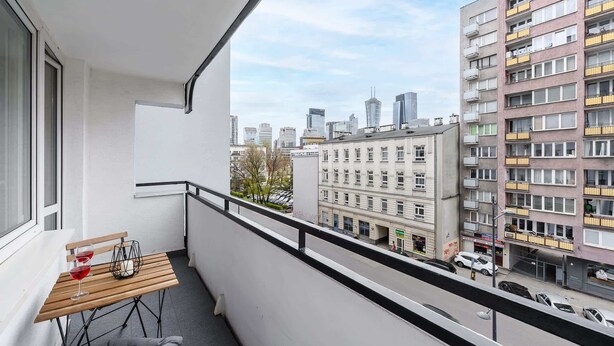Un balcon avec une table, des chaises et une vue sur les bâtiments de la ville.