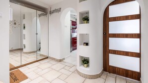 Un couloir moderne avec une porte en bois, des murs en verre et un paillasson.