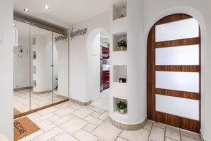 A modern hallway with a wooden door, glass walls, and a welcome mat. - Lumina cozy 3-room apart near the city center (Warszawa)