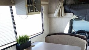 Een compact RV-interieur met een kitchenette, een eethoek en een zithoek.