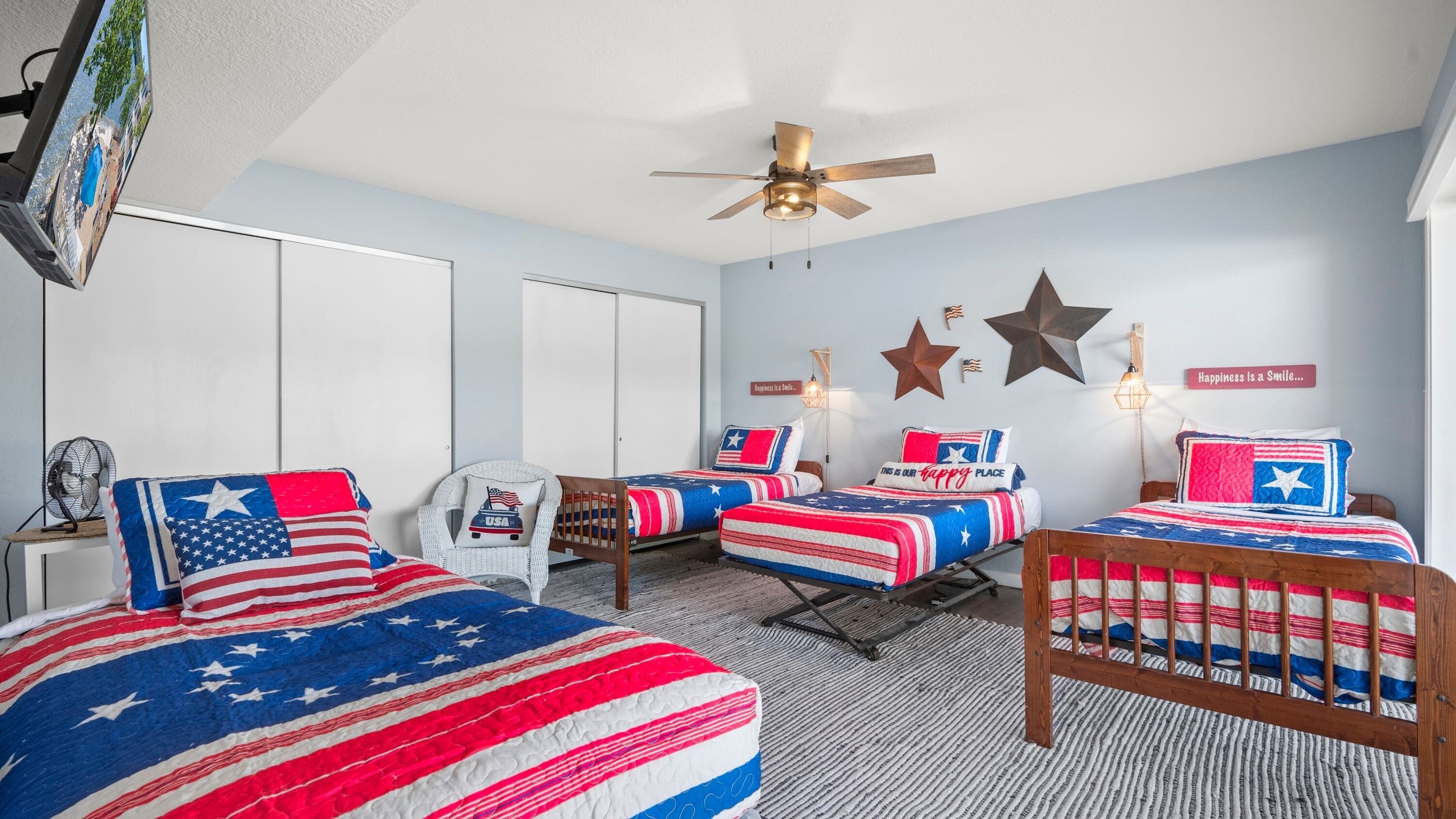 Un dormitorio con dos camas, un ventilador de techo y una pared decorada con estrellas y un cartel.
