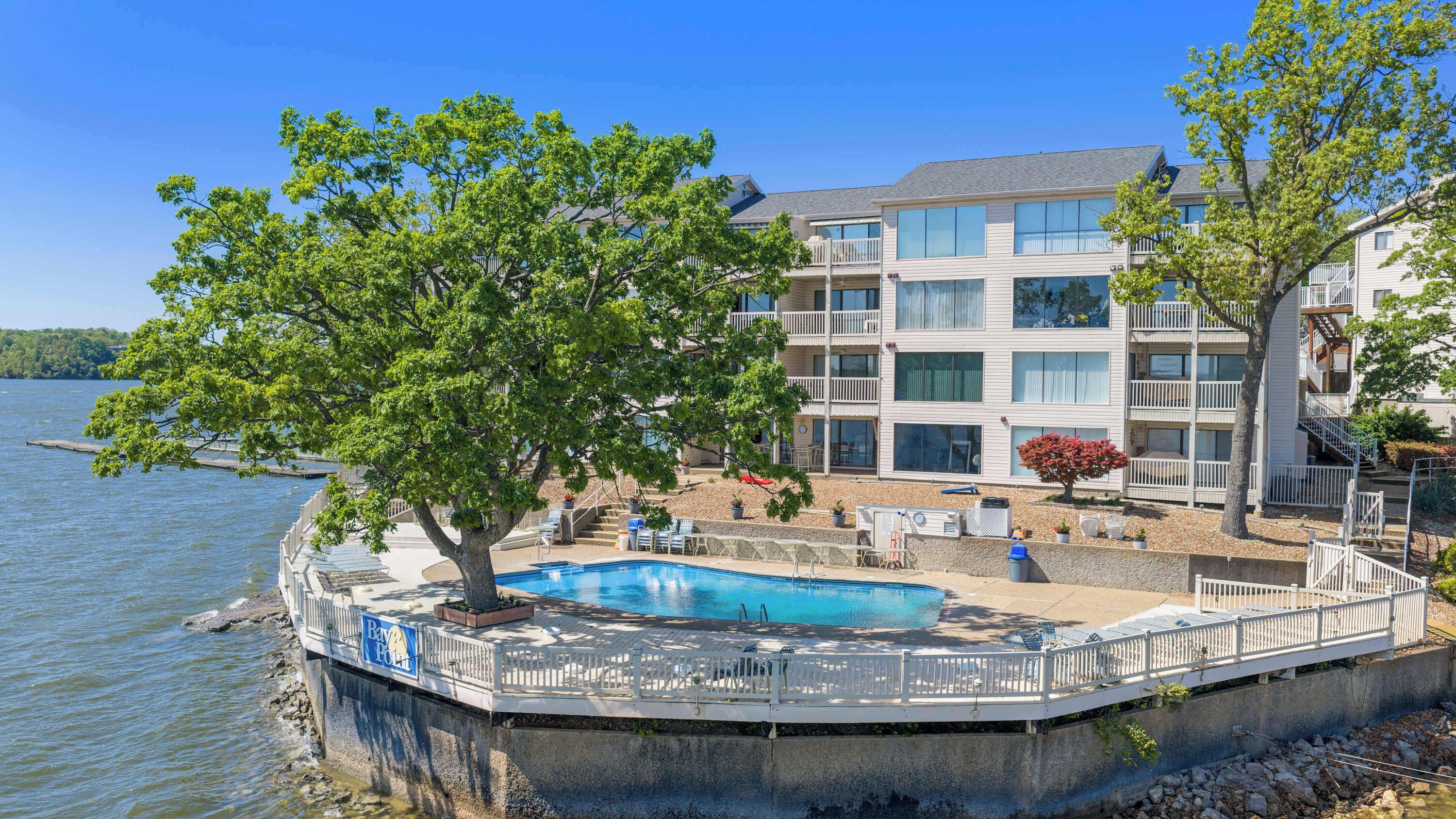 A waterfront hotel with a pool, outdoor seating, and a view of the lake.