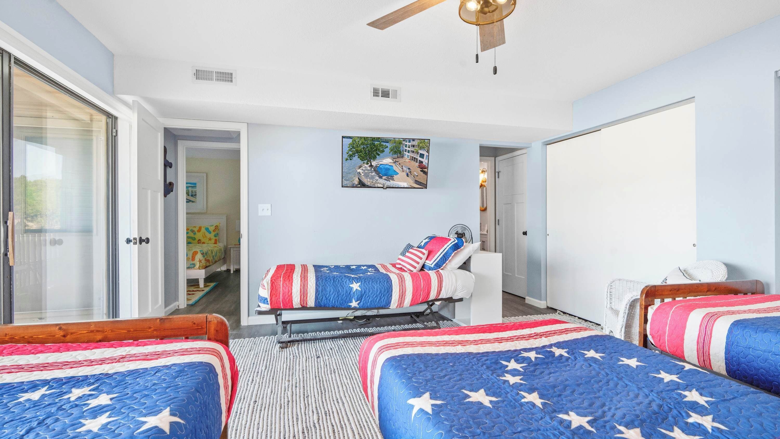 A bedroom with two beds, a ceiling fan, and a painting of a landscape.