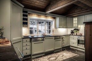 A kitchen with light green cabinets, a black countertop, and a window with a view of parked cars outside.