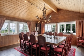 A dining room with a large wooden table, red upholstered chairs, and a chandelier.