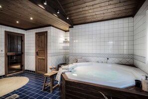 Une salle de spa dotée d’un grand jacuzzi, d’un plancher en bois et d’un mur recouvert de carreaux.