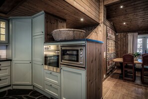 Une cuisine équipée d’appareils électroménagers intégrés, avec des murs en bois et un coin repas comprenant une table et des chaises.