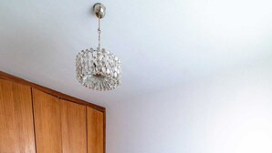 Quarto com cama, guarda-roupa de madeira e luminária pendente.