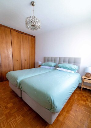 Ein Schlafzimmer mit Bett, Holzschrank und Pendelleuchte.