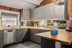 A modern kitchen with grey cabinets, a wooden countertop, and a dishwasher.