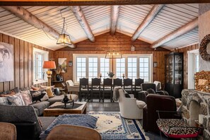 A rustic interior with wooden walls, a dining area, and a stone fireplace.