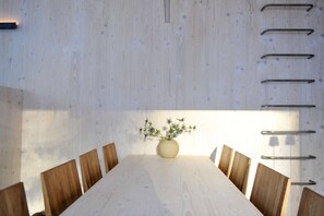 A conference room with a long table, wooden chairs, a vase with flowers, and a wall-mounted rack. - Trysilfjell hytteområde 2027 by Vacation Trysil (Trysil)