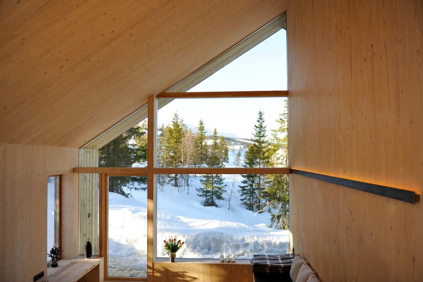 A room with a large window offering a view of a snowy landscape and trees.