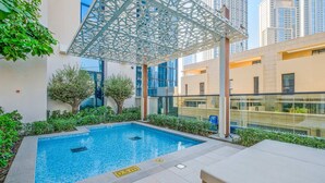 Une piscine dont la profondeur est indiquée à 0,5 mètre, entourée de verdure et de bâtiments modernes.